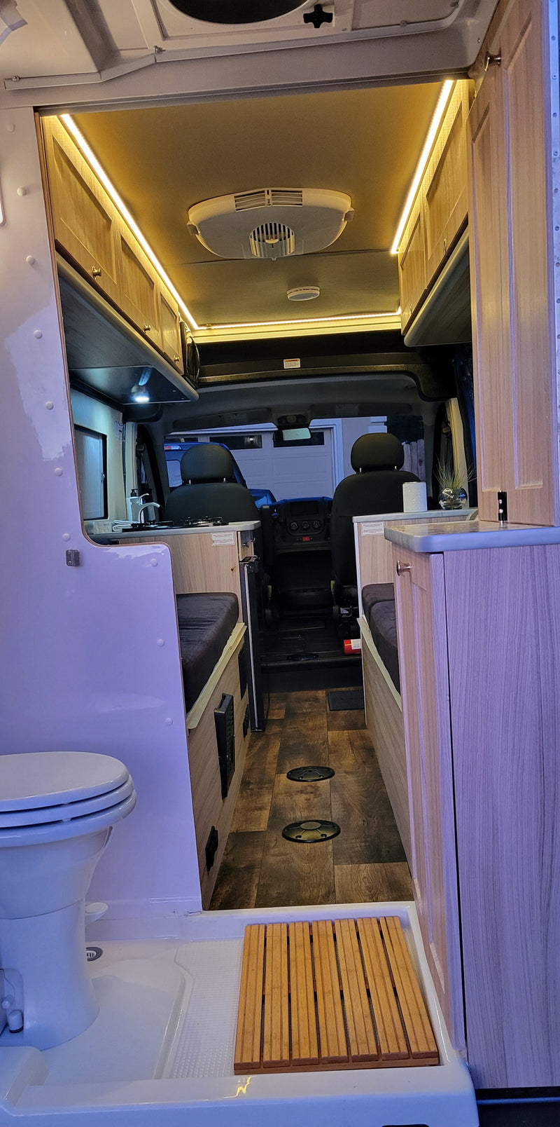 Inside a modern **rv rental**, featuring a compact kitchen, toilet, shower, and cozy sleeping/seating areas. — photo 11