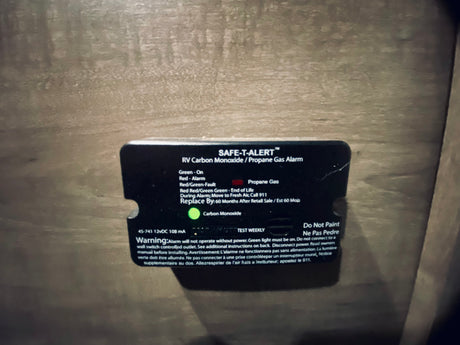 An RV rental's SAFE-T-ALERT Carbon Monoxide/Propane Gas Alarm, with its green light on, indicating active safety monitoring.