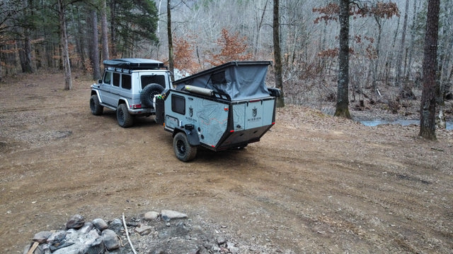 This G-Wagen and Mission Overland camper trailer, ideal for an rv rental, offers off-road overlanding at a forest campsite.