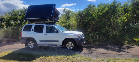 White Nissan Xterra with rooftop tent, ready for adventure camping. Discover unique RV rental options for your next trip.