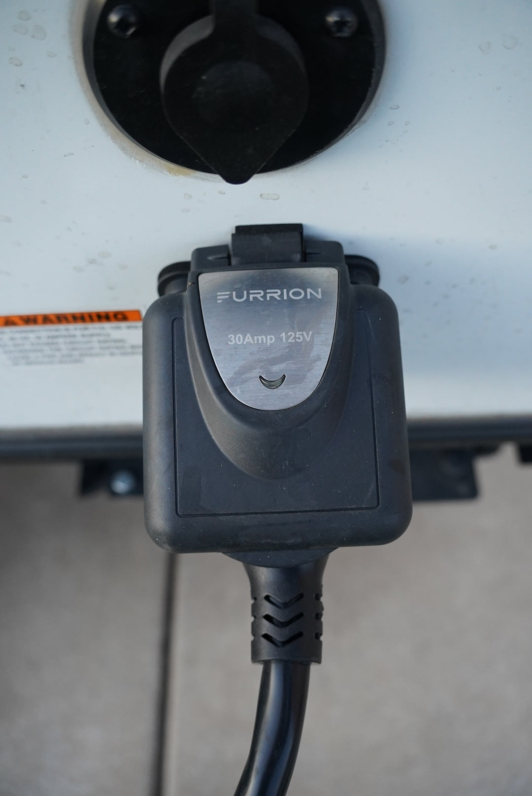 RV rental's 30 Amp 125V Furrion power cord plugged in, ensuring electrical hookup for shore power.