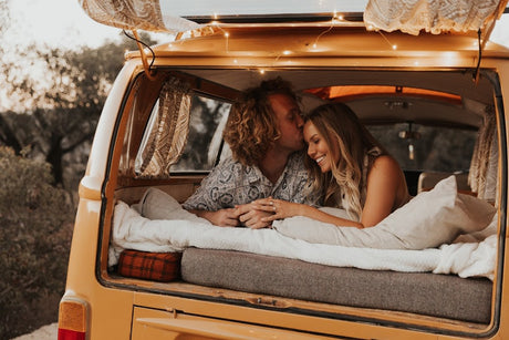 Cozy rv rental romance: A smiling couple shares a tender kiss in the back of their vintage campervan, surrounded by comfort.