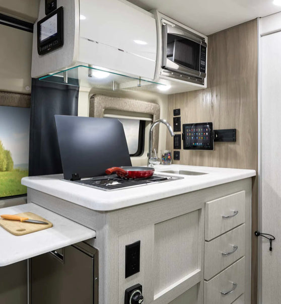 Modern RV rental kitchen with stove, sink, microwave, tablet mount, and sleek cabinets, ideal for road trips. — photo 17