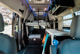 Spacious rv rental camper van interior with an elevated bed, Dometic fridge, and a functional kitchenette for travel.