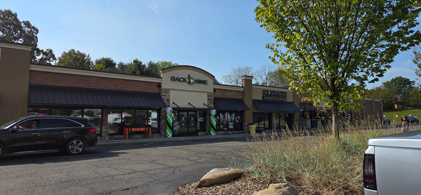 A vibrant commercial strip with 'Back b Nine' indoor golf & 'Elevate' chiropractic. A great stop after an RV rental adventure!