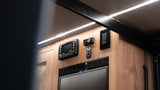 Advanced electronics in this RV rental: Redarc RedVision power management, bed lift, and fridge controls on a wood panel.