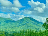 Lush green mountains beneath a cloudy blue sky. Perfect RV rental scenery for outdoor adventures.