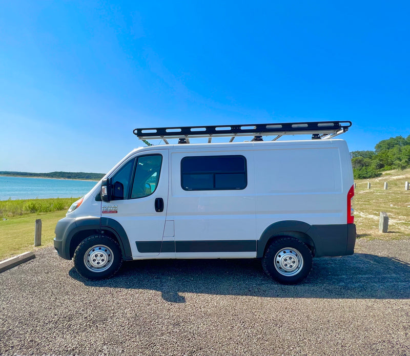 This white Ram ProMaster camper van with a roof rack, parked by a scenic lake, could be your next RV rental! — photo 15