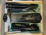 Organized RV rental kitchen drawer, featuring spatulas, a whisk, measuring cups, a digital thermometer, and kitchen shears.