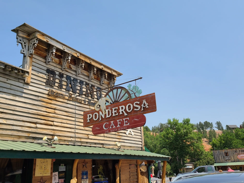 A rustic wooden building, the Ponderosa Cafe, with a large 'Dining' sign, an inviting stop on your RV rental road trip.