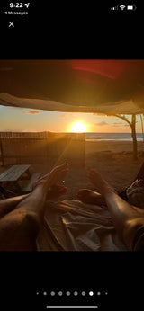 RV rental adventure: feet up, enjoying a stunning sunset over the ocean from a cozy beachside retreat. Perfect relaxation.