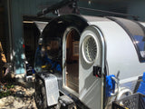 Compact teardrop travel trailer RV rental with open door revealing interior and step. Ready for your next trip!