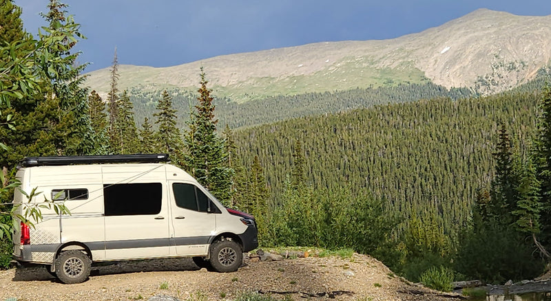  overlooking vast mountain ranges and dense pine forests.|This light-colored Mercedes-Benz Sprinter camper van — photo 2