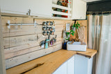 Organized RV rental kitchen interior: wooden backboard, magnetic spice rack, sink, and storage solutions.