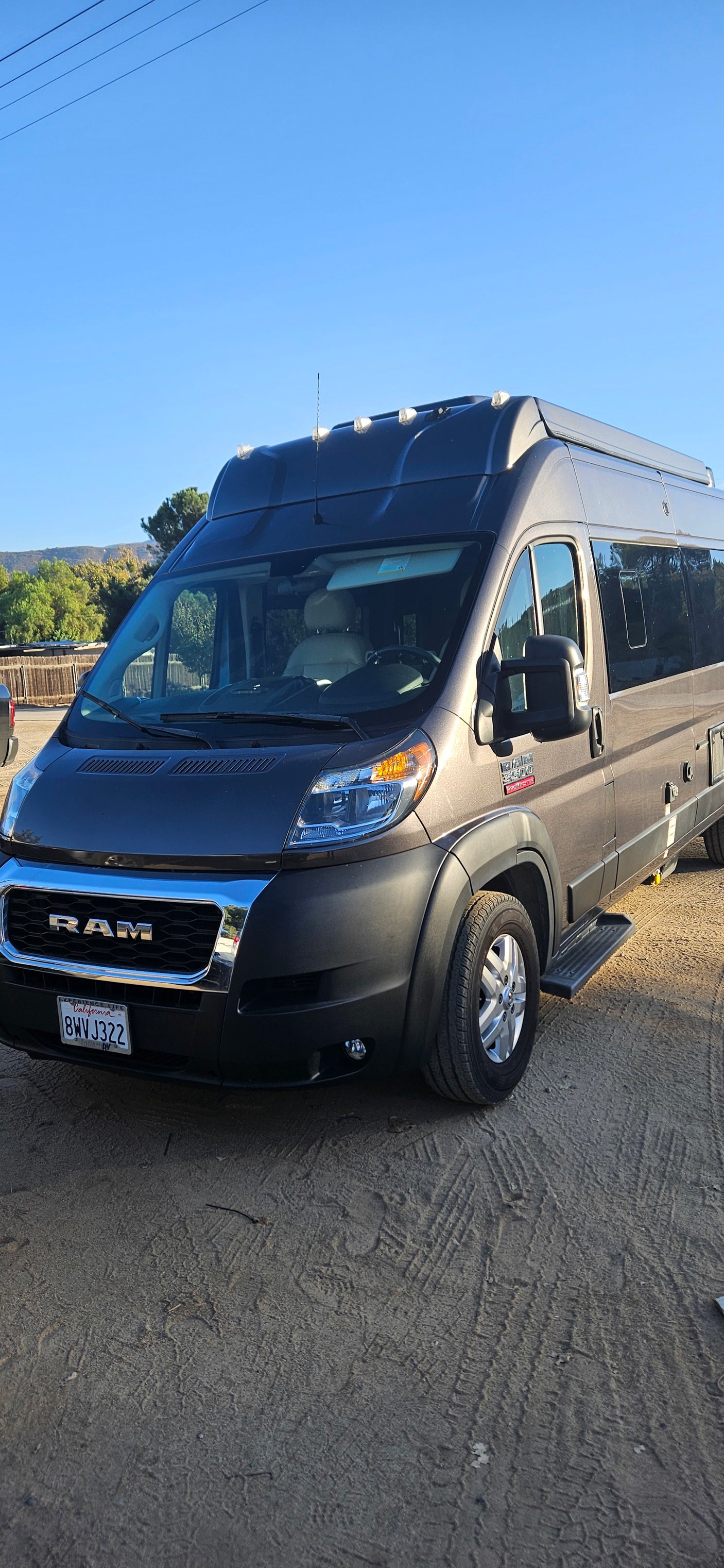 Gray high-roof Ram ProMaster camper van, parked on dirt. Perfect for your next RV rental.