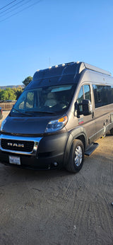 Gray high-roof Ram ProMaster camper van, parked on dirt. Perfect for your next RV rental.