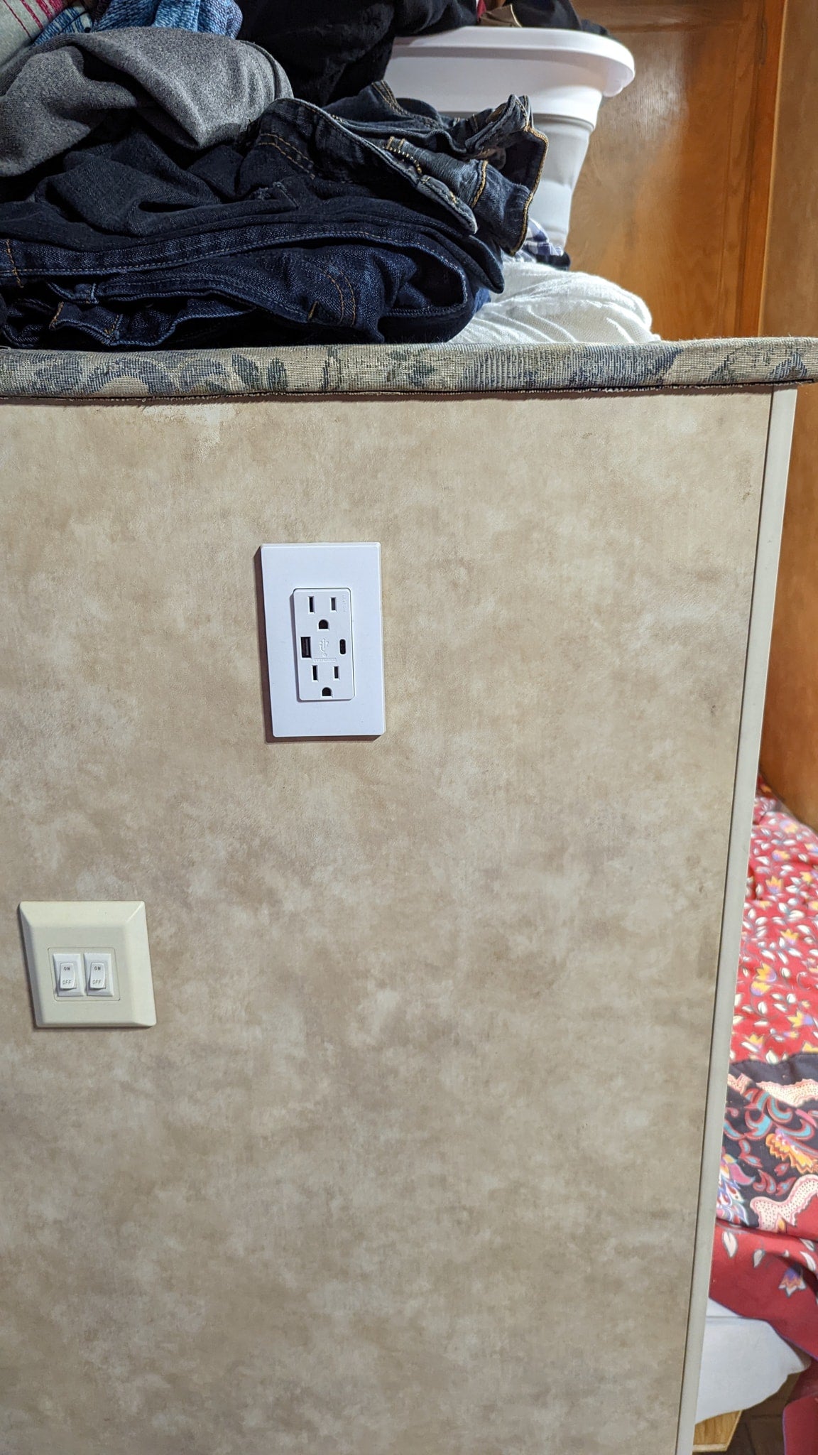 Inside an rv rental: Folded laundry on a counter, with an electrical outlet (featuring USB ports) and light switches on the wall. — photo 16