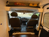 Inside an RV rental campervan, showing the front cab, driver/passenger seats, and overhead bed/storage area.