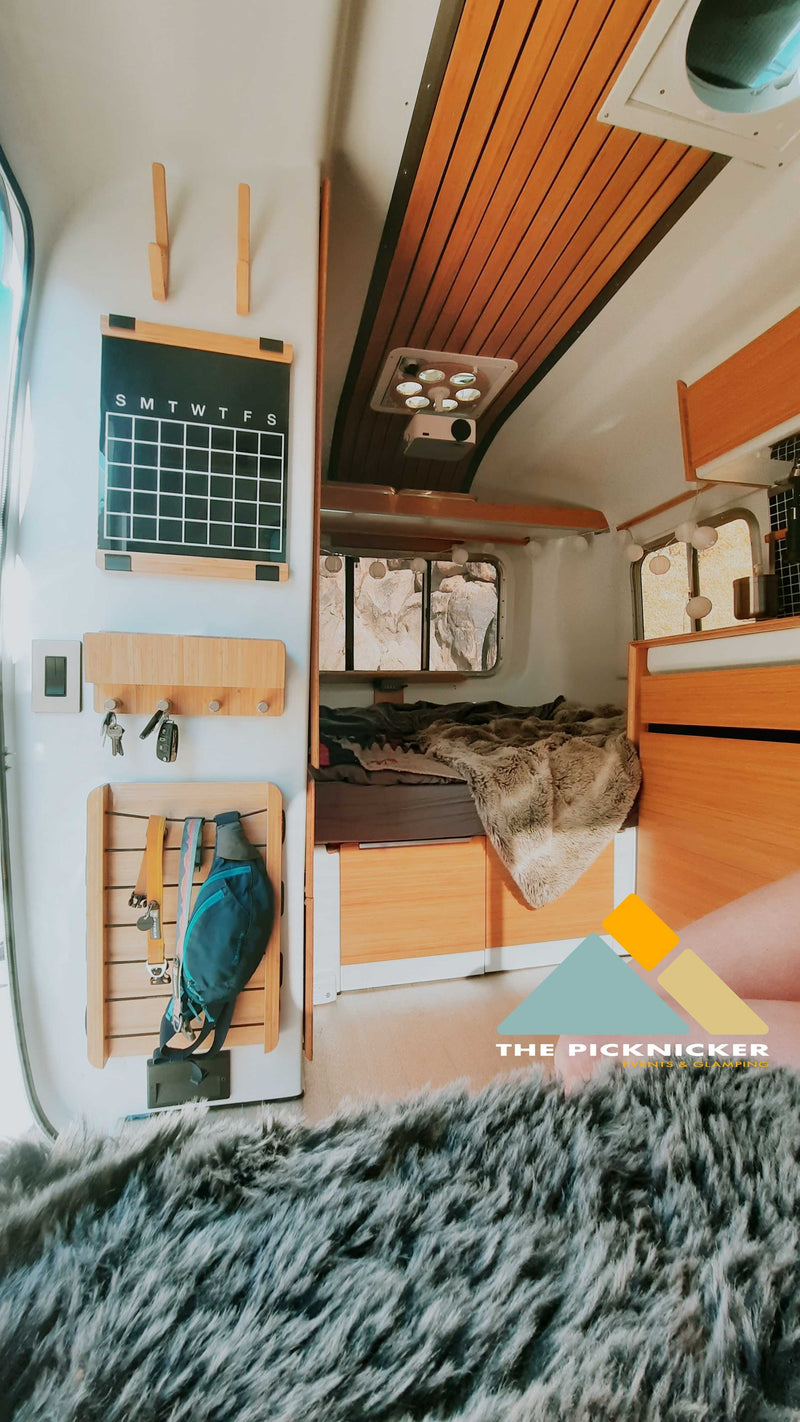 Cozy RV interior featuring a comfy bed, wall organizer, projector, and furry rug. Perfect for your next RV rental adventure! — photo 4