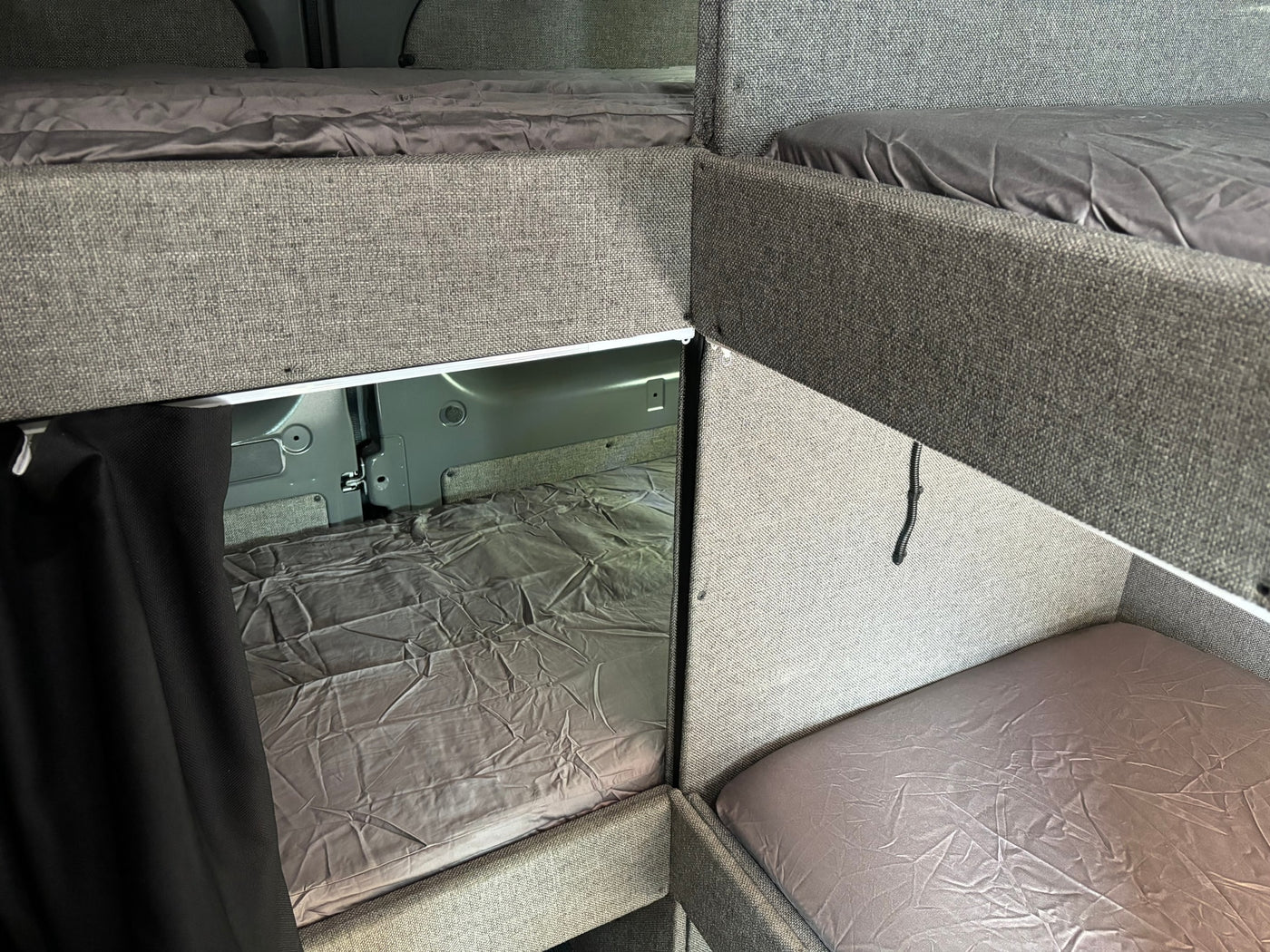 Inside an RV rental: multiple bunk beds with grey sheets, maximizing sleeping space in a compact camper van. — photo 4