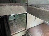 Inside an RV rental: multiple bunk beds with grey sheets, maximizing sleeping space in a compact camper van.
