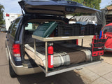 RV rental SUV setup with custom bed, cooking gear on a shelf, and fire extinguisher for car camping adventures.
