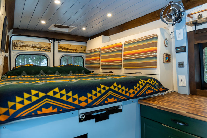 Cozy RV rental interior: a comfortable bed with colorful patterned blanket — photo 1