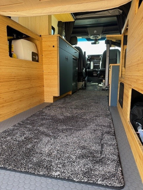  & dark cabinetry along a plush rug runner.|Modern RV rental interior: Custom camper van kitchen with bamboo & blue cabinets — photo 6