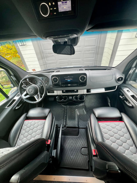 Inside a Mercedes-Benz Sprinter RV rental: Modern cockpit with custom seats, dashboard, and infotainment screen. Ready for adventure!