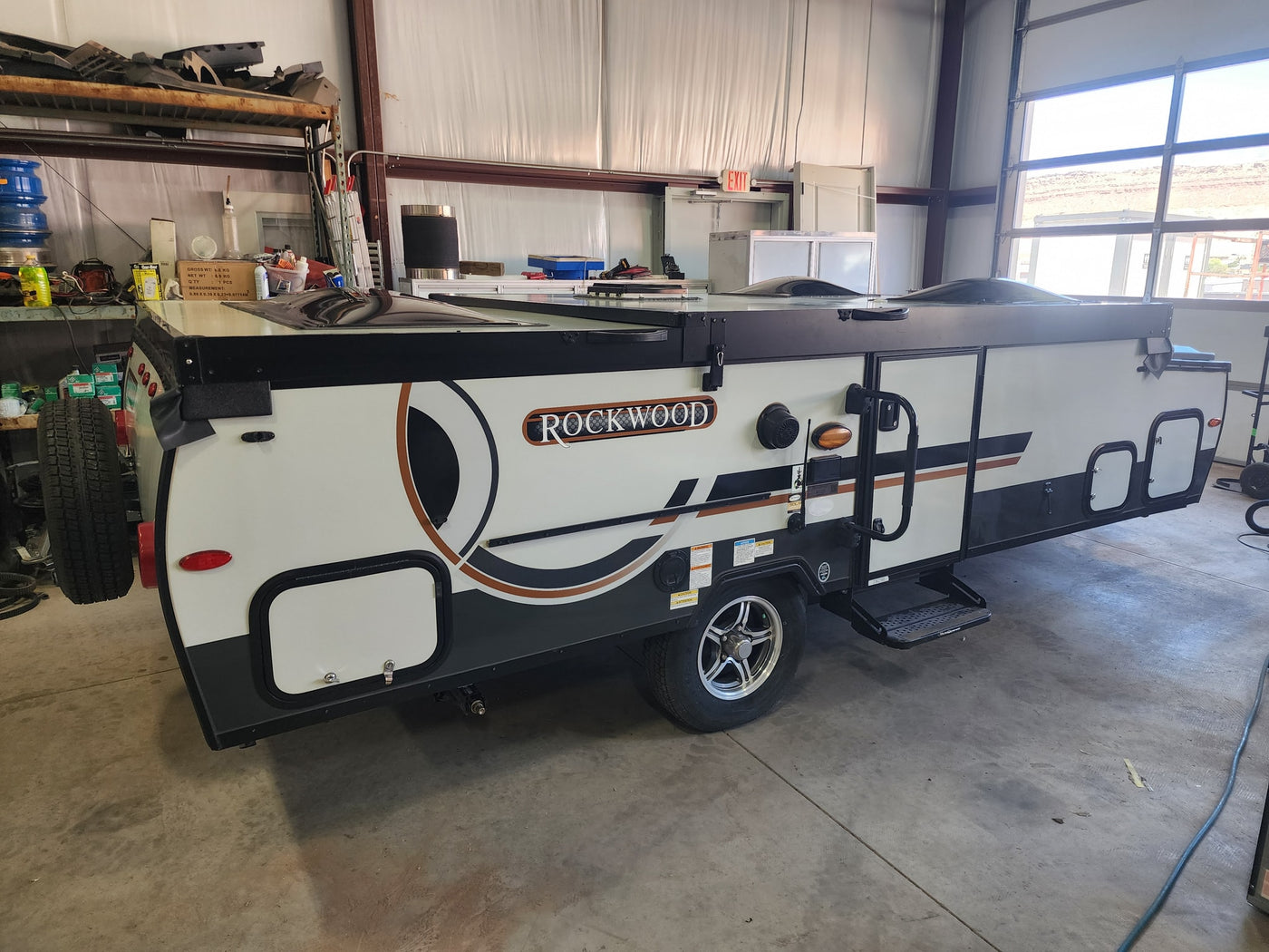 Rockwood pop-up camper, ready for RV rental, parked indoors. This compact recreational vehicle features a sleek design. — photo 10