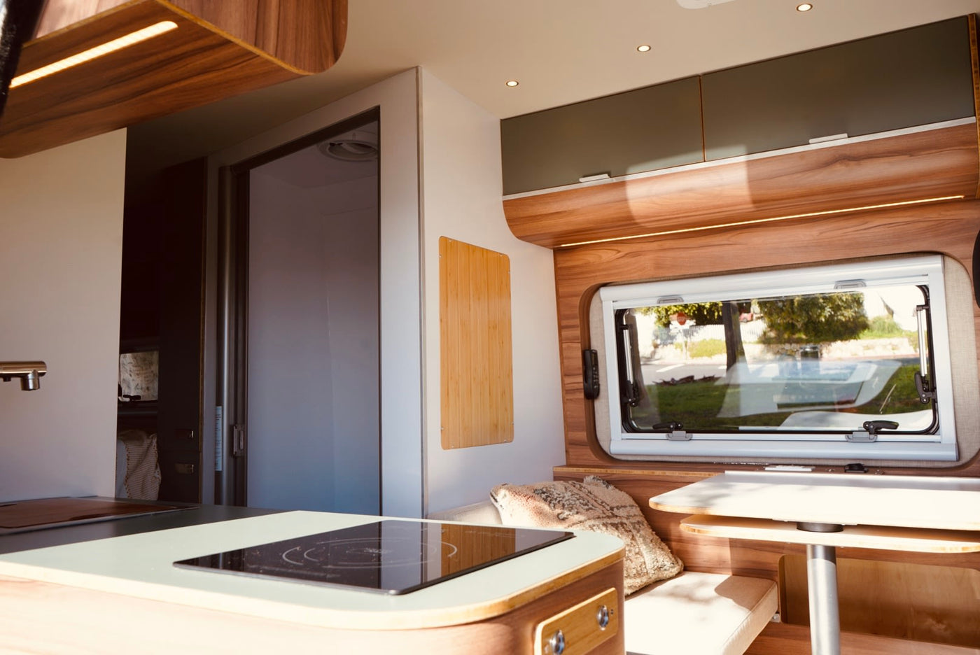  under a clear blue sky.|Silver camper van RV rental parked by the ocean on a sunny day. Perfect for a scenic coastal adventure.|Step inside this stylish RV rental! Features a modern kitchen — photo 9