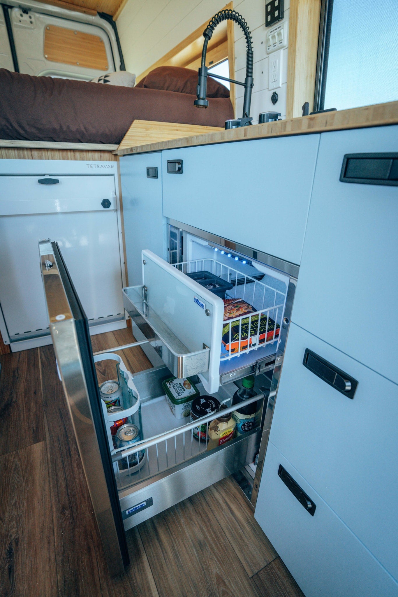  and a warm wooden ceiling.|Modern RV rental camper van interior: compact kitchen — photo 8