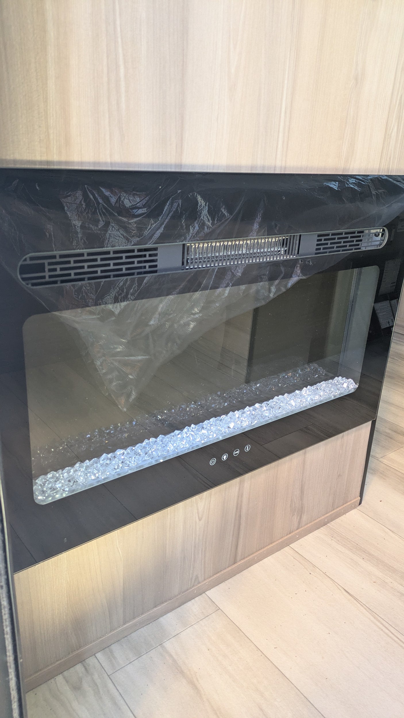 This new electric fireplace in an RV rental interior shows protective film and decorative crystals, ready for use.