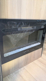 This new electric fireplace in an RV rental interior shows protective film and decorative crystals, ready for use.