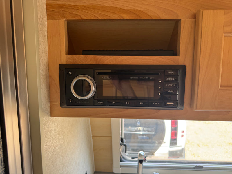 Jensen JWM70A RV stereo in wooden cabinetry of an rv rental, with Bluetooth, HDMI, and USB. Remote visible above. — photo 14