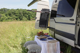 Picnic beside a 27 NORTH camper van with gear rack, ideal for an rv rental outdoor adventure.