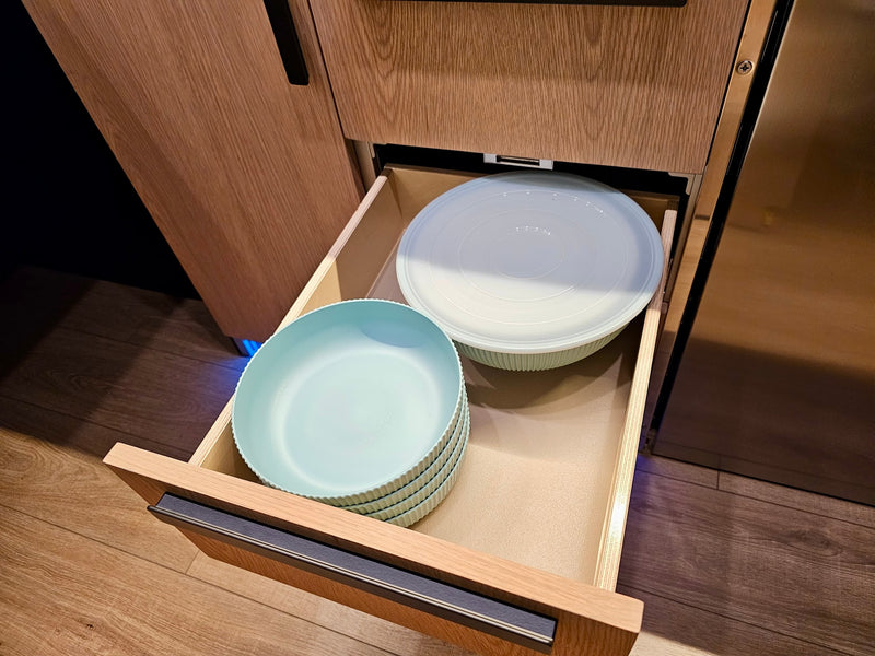 Inside an RV rental, an open kitchen drawer reveals light blue dishes and a lidded bowl, perfect for compact storage. — photo 13