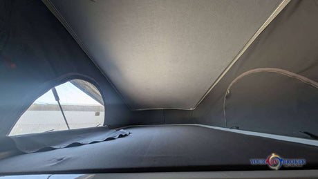 Inside an rv rental camper van, showcasing the pop-top sleeping area with a bed and an open canvas window for bright views and camping.
