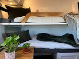 Cozy bunk beds in an RV rental interior, with soft green bedding and plants, perfect for comfortable sleeping on your adventure.