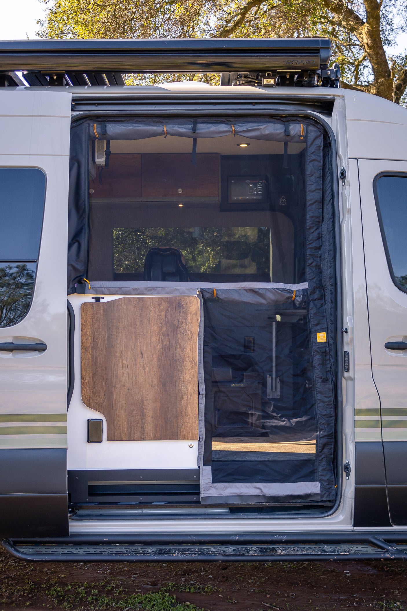 Spacious RV rental with an open side door, revealing a mesh screen, interior control panel, and steps. Perfect for adventure.