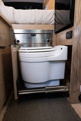 Compact pull-out toilet in an RV rental, nestled under a bed for clever space-saving and comfort on the road.
