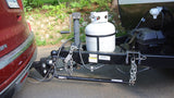 RV rental trailer's complete towing setup: hitch, safety chains, propane tanks, battery, and weight distribution bars.