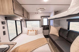 RV rental interior features a cozy bedroom with bunk beds, a comfy couch, and large windows. Ready for adventure!
