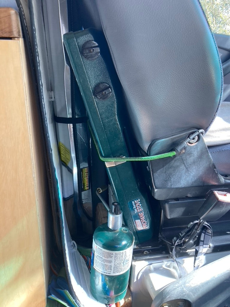 Essential camping gear for your rv rental: a portable propane stove and tank neatly stored next to the seat.