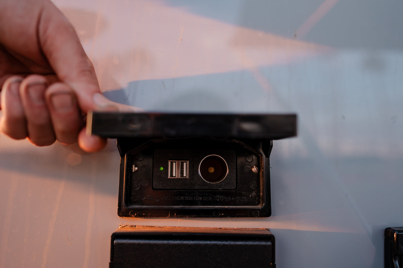A hand opens an RV power outlet showing USB and 12V ports, vital for charging devices on your rv rental trip.
