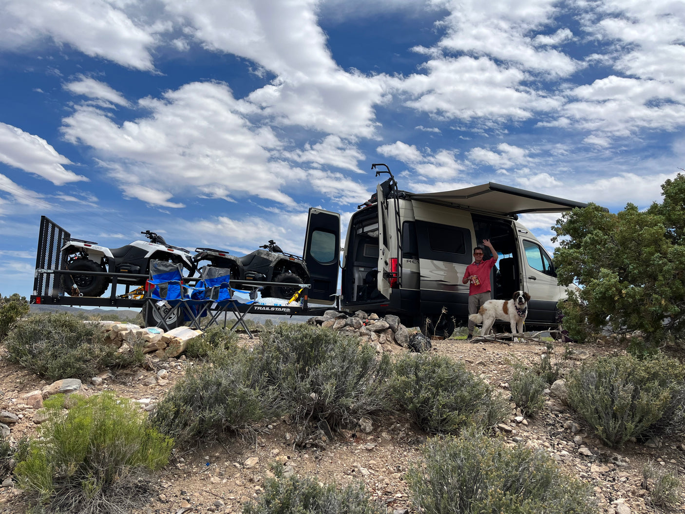 Adventure awaits! An RV rental with ATVs, a man, and his dog are ready for off-road fun in the desert.