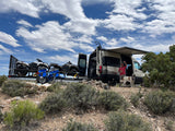 Adventure awaits! An RV rental with ATVs, a man, and his dog are ready for off-road fun in the desert.