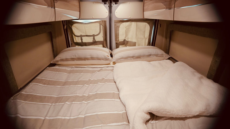 Inside an RV rental: a neat, comfortable bed with striped bedding & a fluffy white blanket, ready for travel. — photo 5