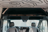 Inside this chic rv rental, see the front cabin of a custom camper van with a unique contour map headliner & overhead bed.