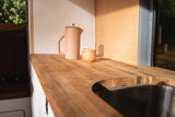 RV rental kitchen detail: light wood countertop, sink, and a matching coffee pot with cup.